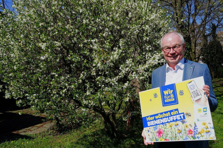 Stephan Pernkopf vor einem weiß blühenden Gehölz mit Wir für Bienen Schild